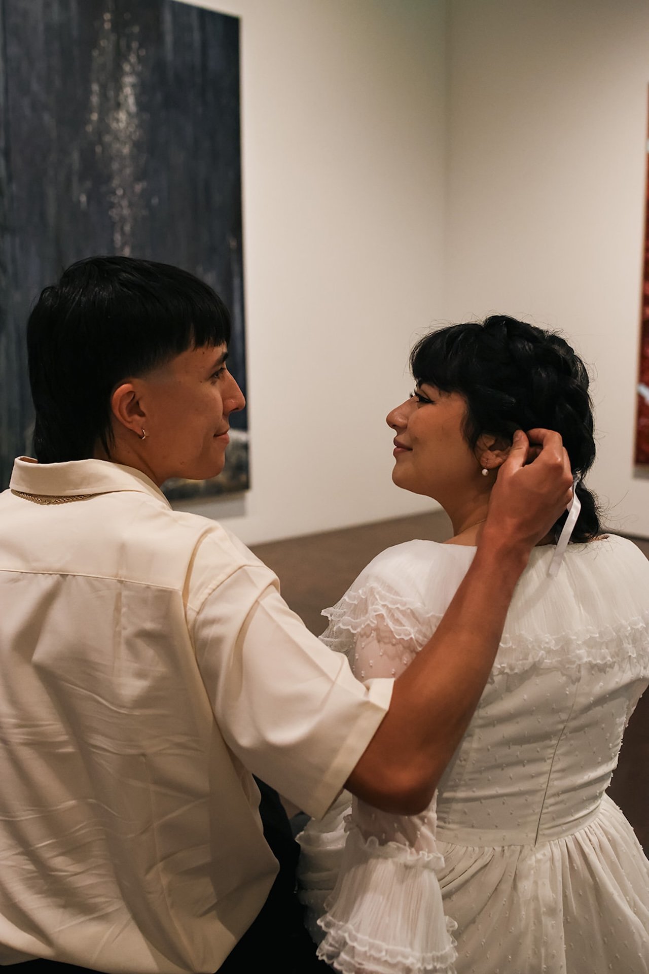 A tender portrait of the guy gently tucking hair behind his fiances ear as they sit close together, creating emotional and intimate city engagement photos indoors.