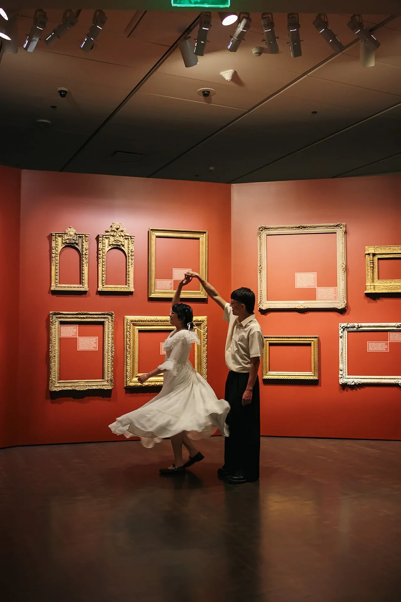 A couple twirling in front of an art gallery wall during their engagement session at the Denver Art Museum