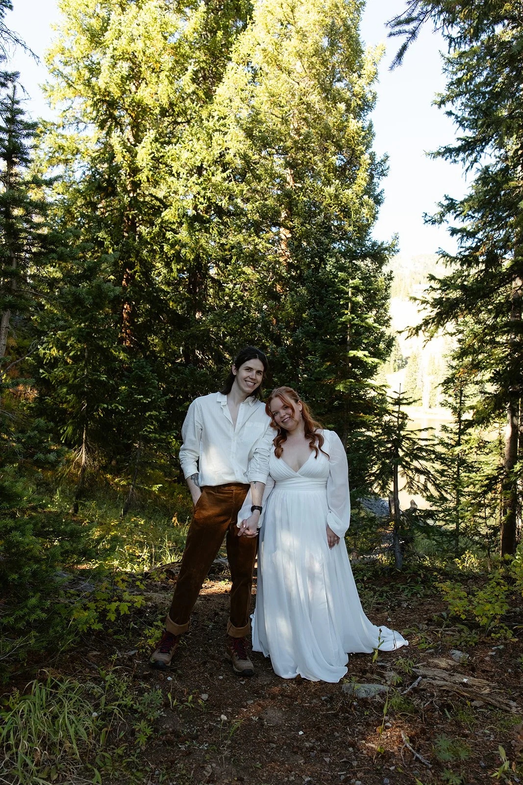 The bride and groom standing hand in hand and smiling at the camera with aspens all around them during their Crested Butte Elopement
