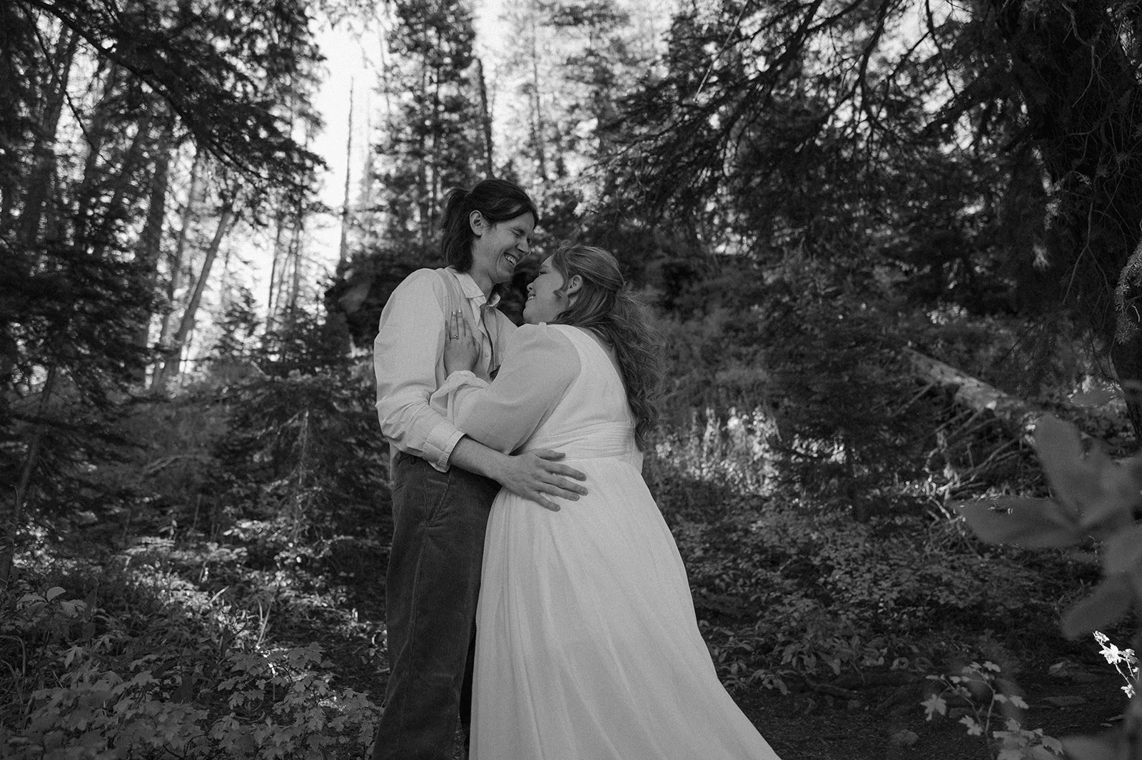 Black and white image of the bride and groom smiling and laughing together during their intimate Crested Butte elopement in the woods.