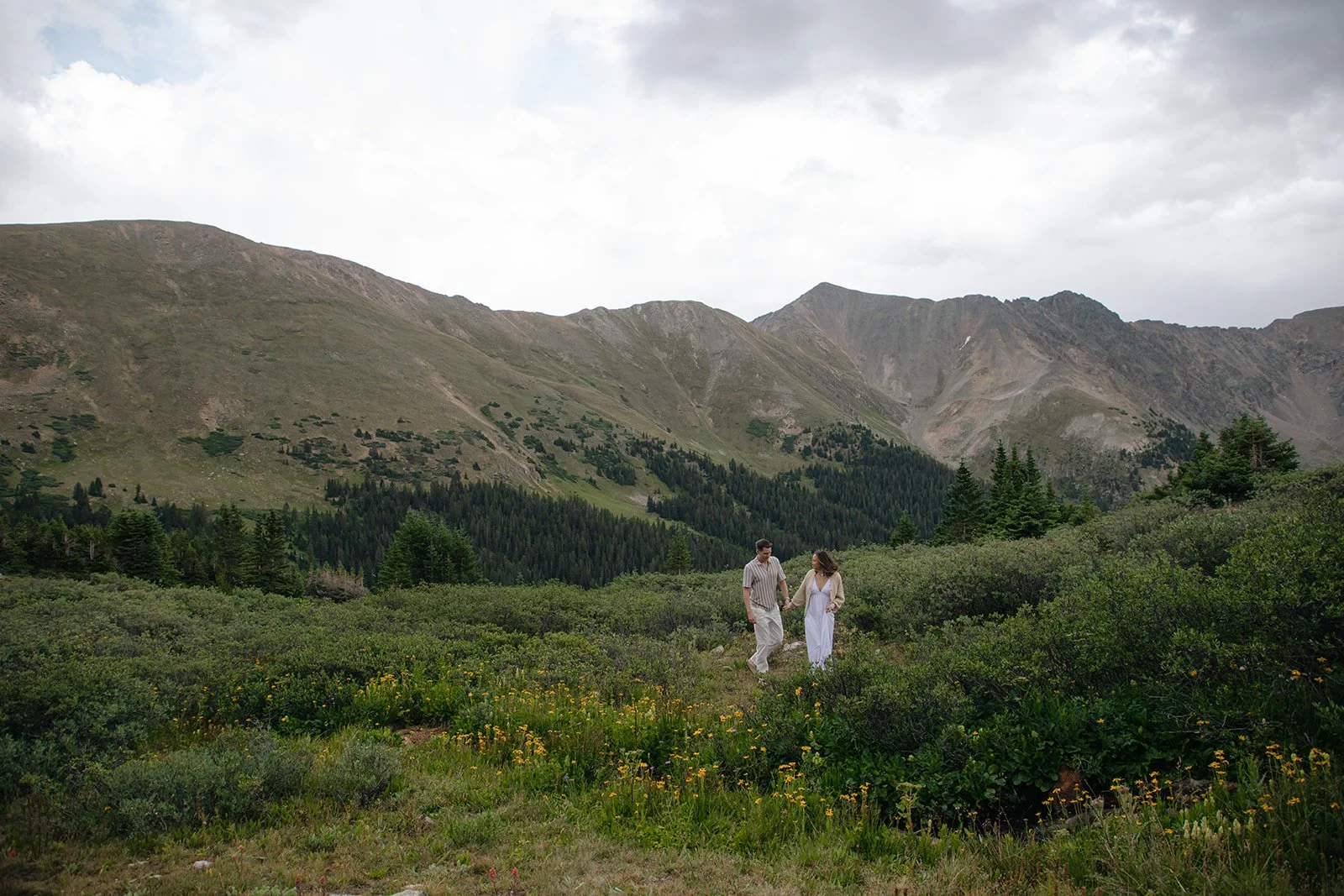 a couple walking through the wildflower at a beautiful Engagement Photo Location in Colorado