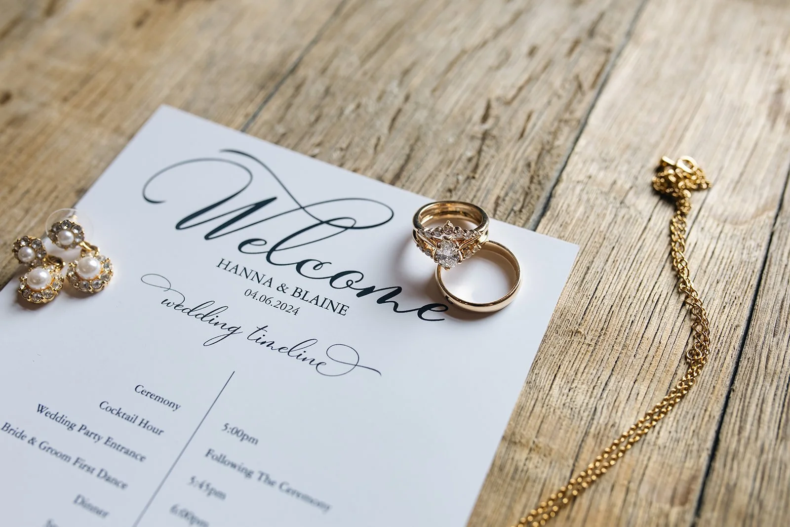 a flatlay with the wedding invitation with gold jewelry laying on it