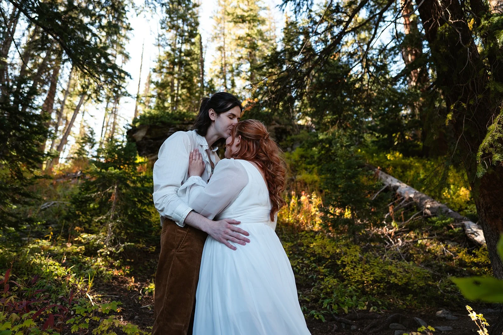 A photo of the bride and groom smiling and laughing together during their intimate Crested Butte elopement in the woods.