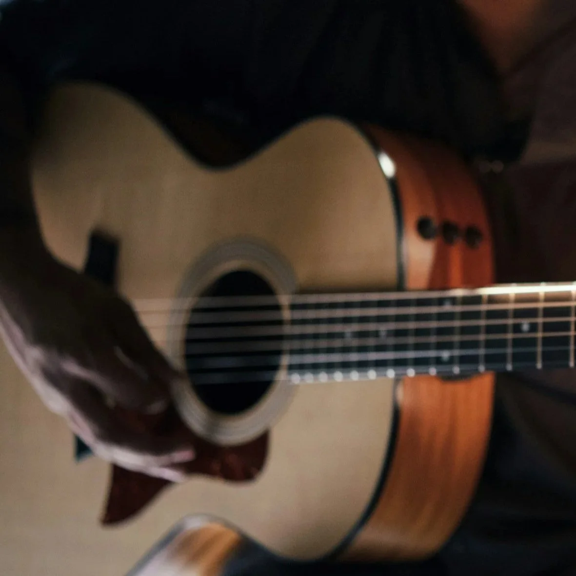 Close-up of an acoustic guitar being played, focusing on the sound hole and strings.