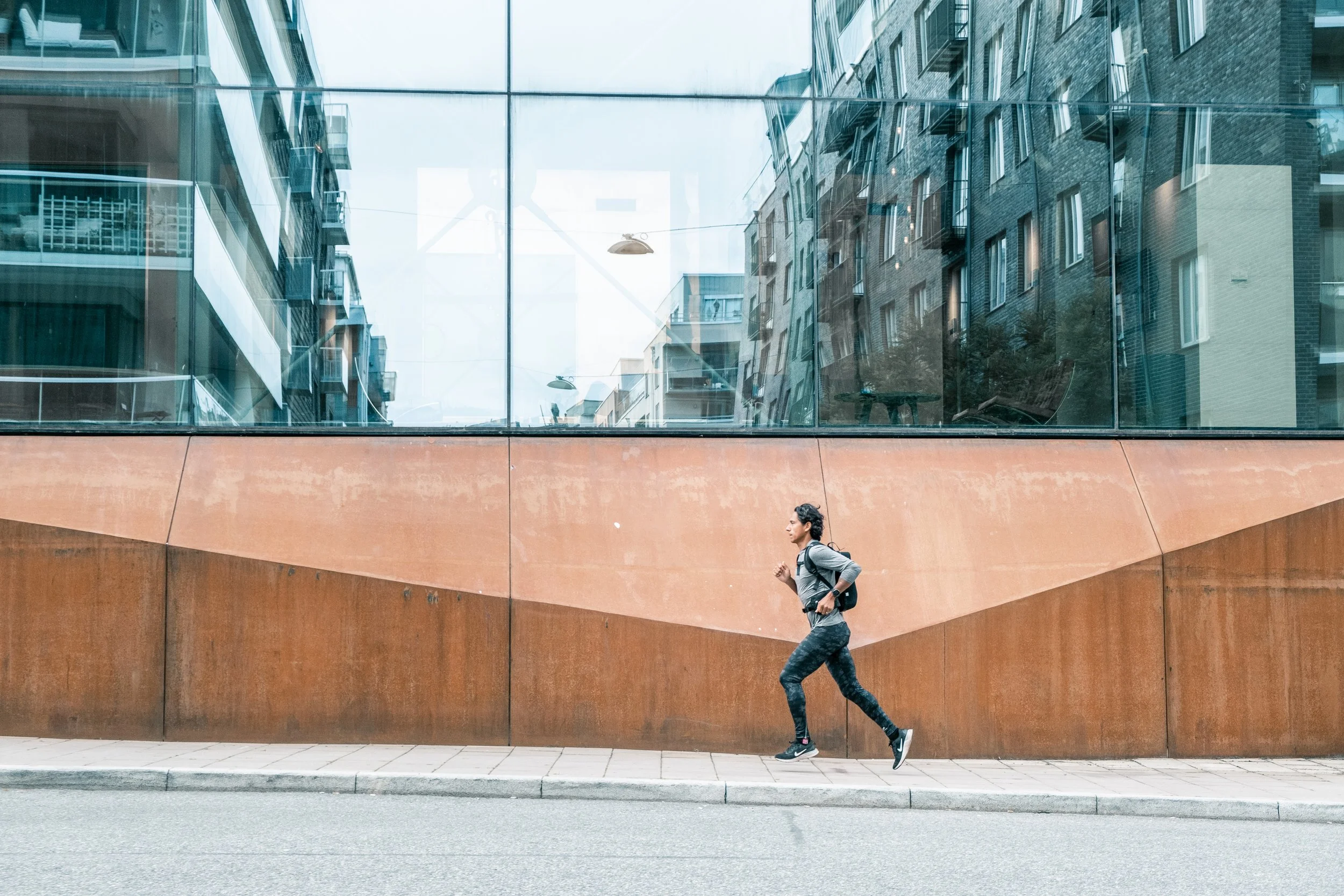 Runner passing a modern glass building in the city