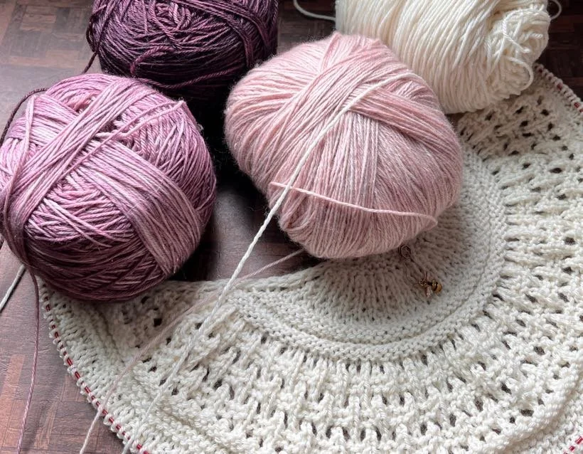 Knitting project in progress with varied colors of pinks and white