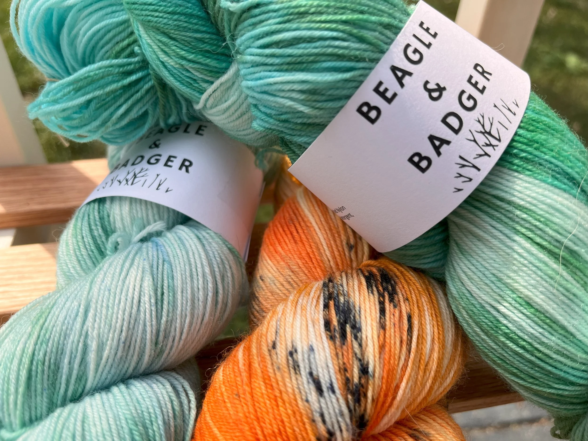 Skeins of orange yarn with black speckles and a green blue yarn