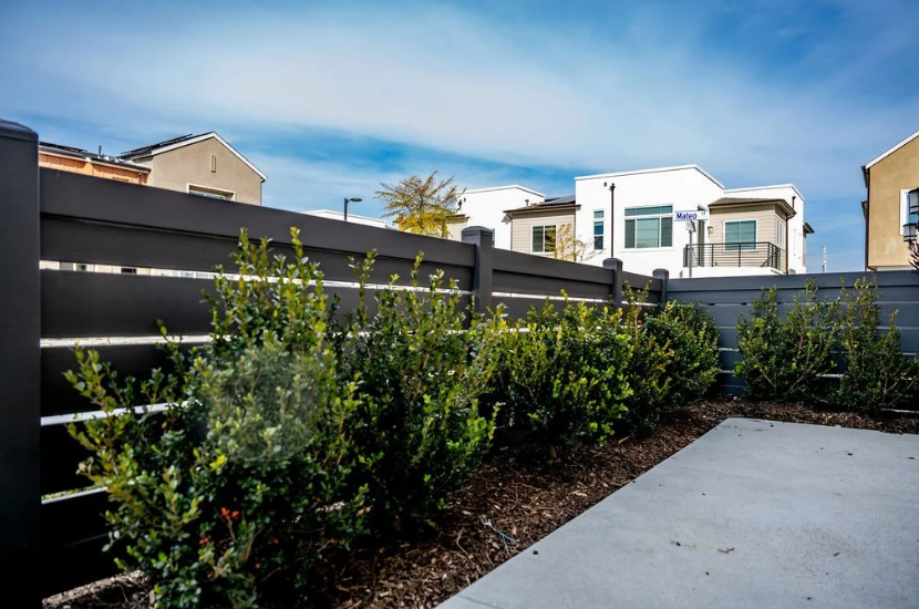 Black residential privacy fence with horizontal slats surrounding a poolside yard.