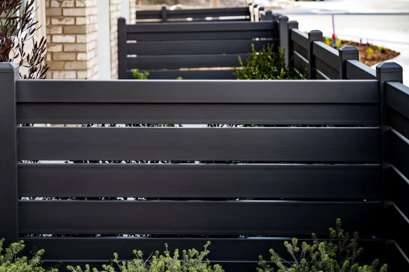 Black residential privacy fence with horizontal slats in a contemporary yard.