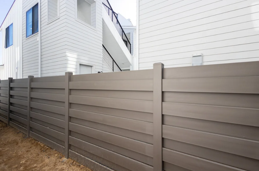 Galvanized steel residential privacy fence with horizontal slats beside a modern home exterior.