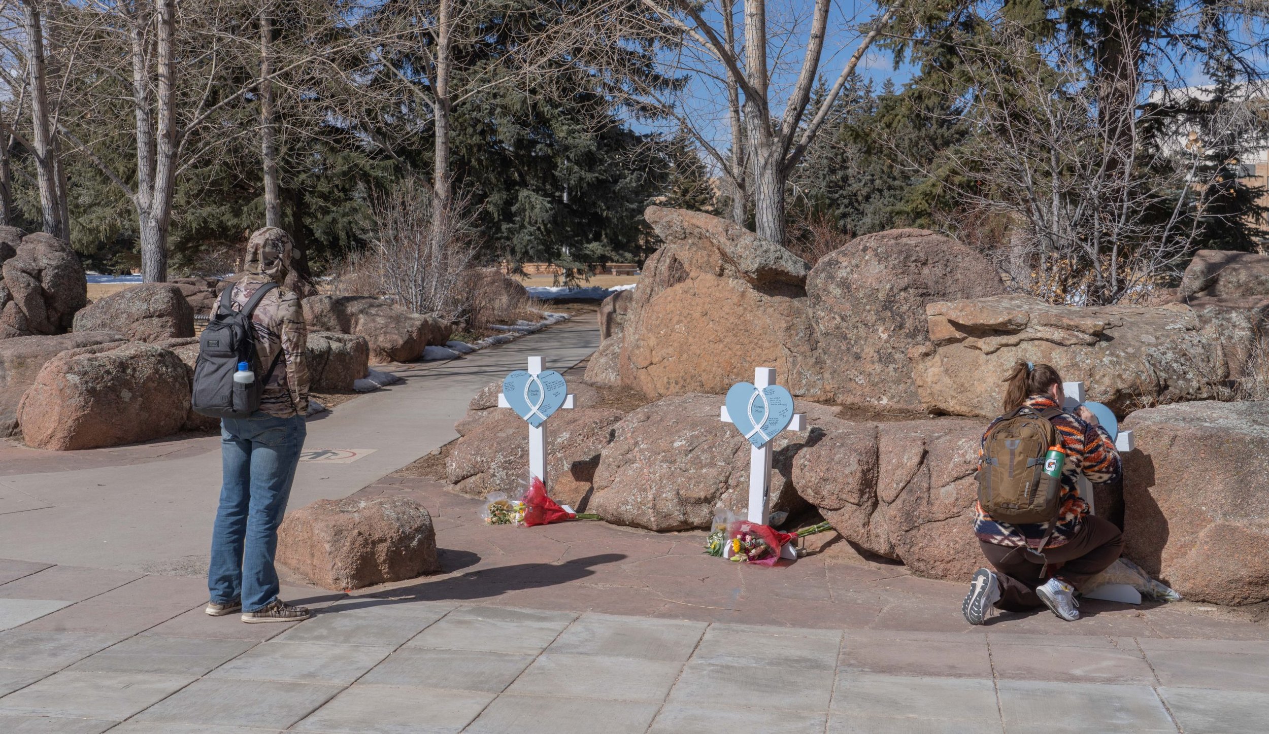 Mourners pause Monday, Feb. 26, 2024, in front of a memorial honoring three members of the University of Wyoming swim and diving team who died days earlier in a car crash.//WyoFile Friday Photo Column