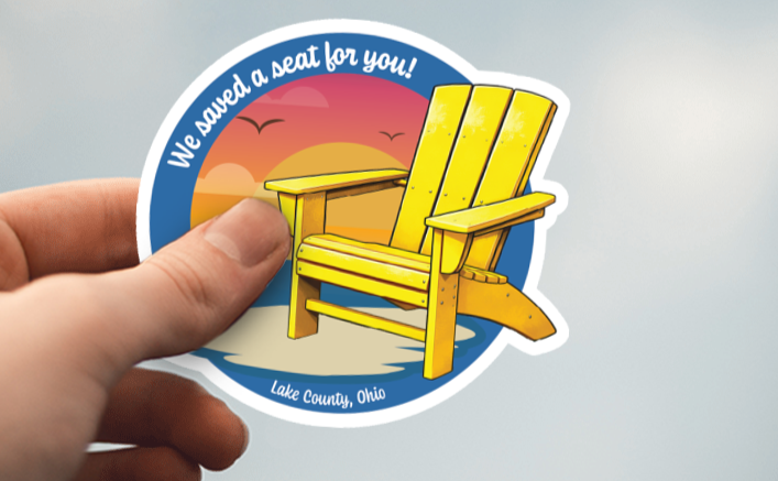We saved a seat for your sticker that features a yellow Lake County Adirondack chair with a sunset in the background