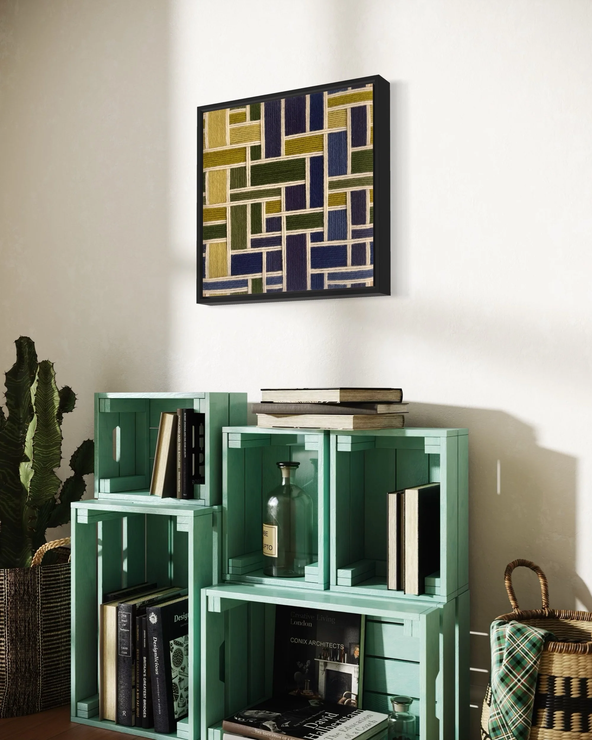 Decorative wall hanging with abstract geometric pattern in green, blue, yellow, and white, mounted on a white wall. Below, turquoise wooden crates are used as a bookshelf, filled with books and decorative items, next to a wicker basket and a large gr