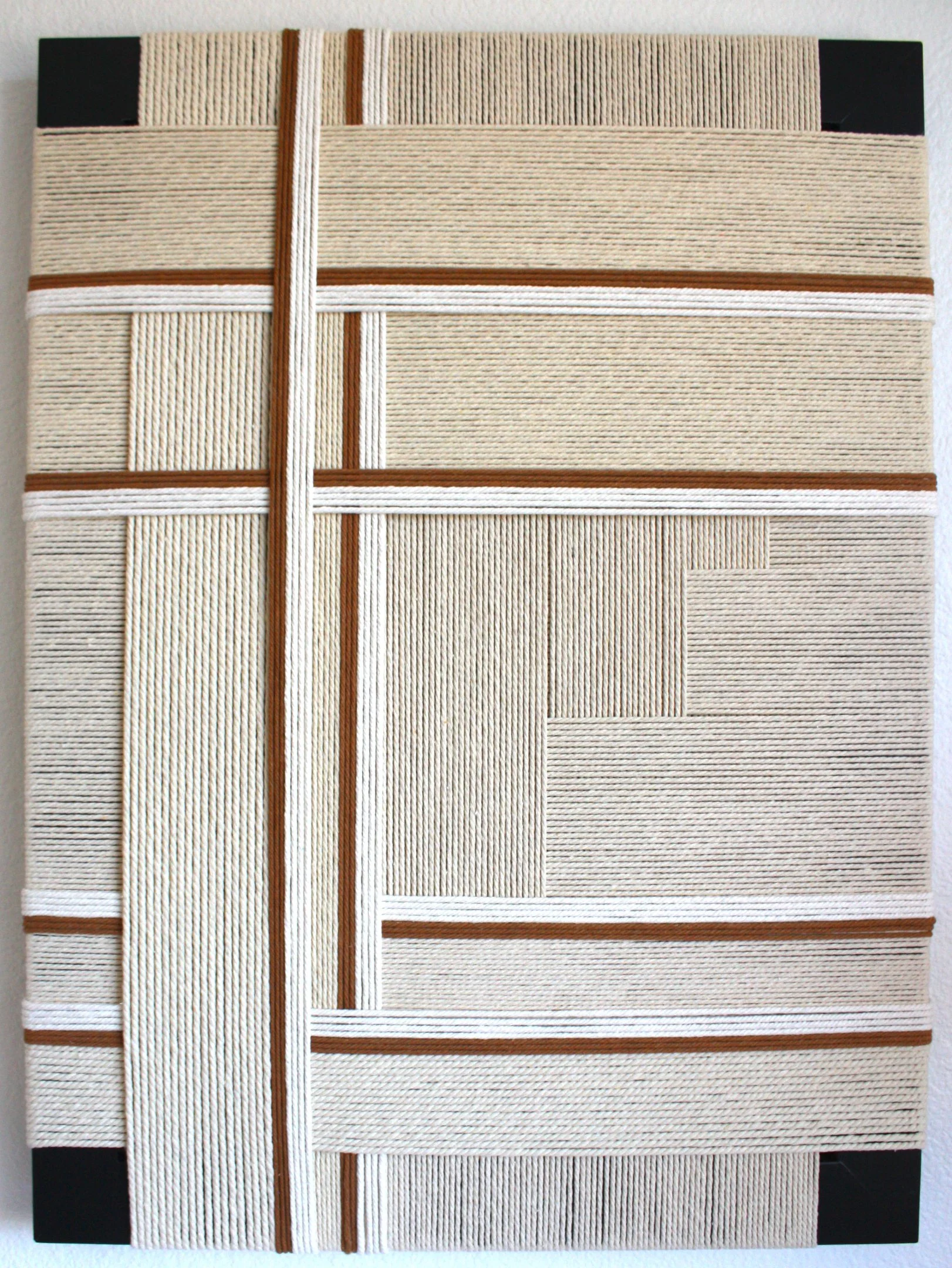 A wall hanging or tapestry with a woven geometric pattern of horizontal and vertical lines in beige, white, and brown colors.