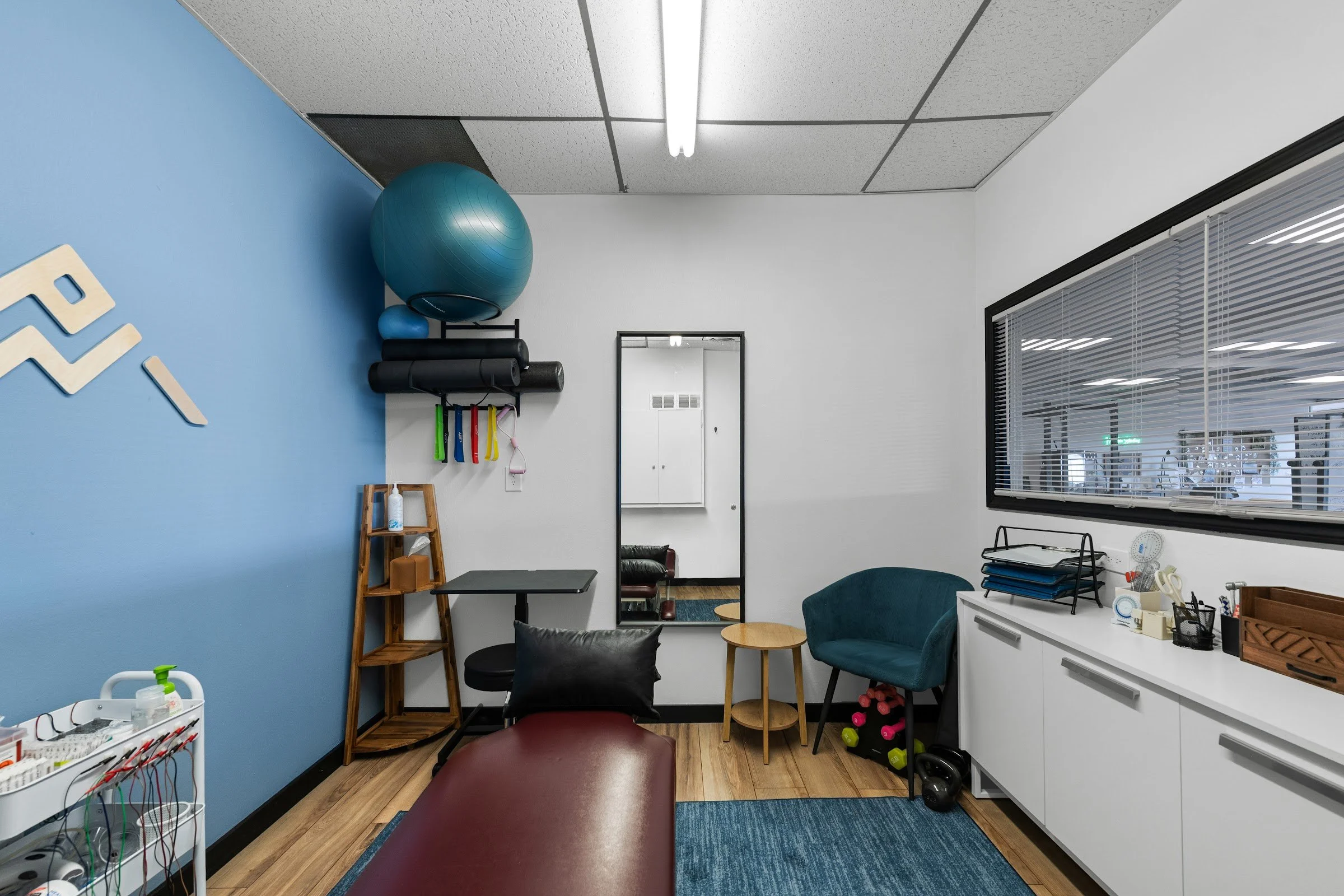 Physical therapy room with treatment table, exercise ball, and mirror at Mountain Shadows CrossFit