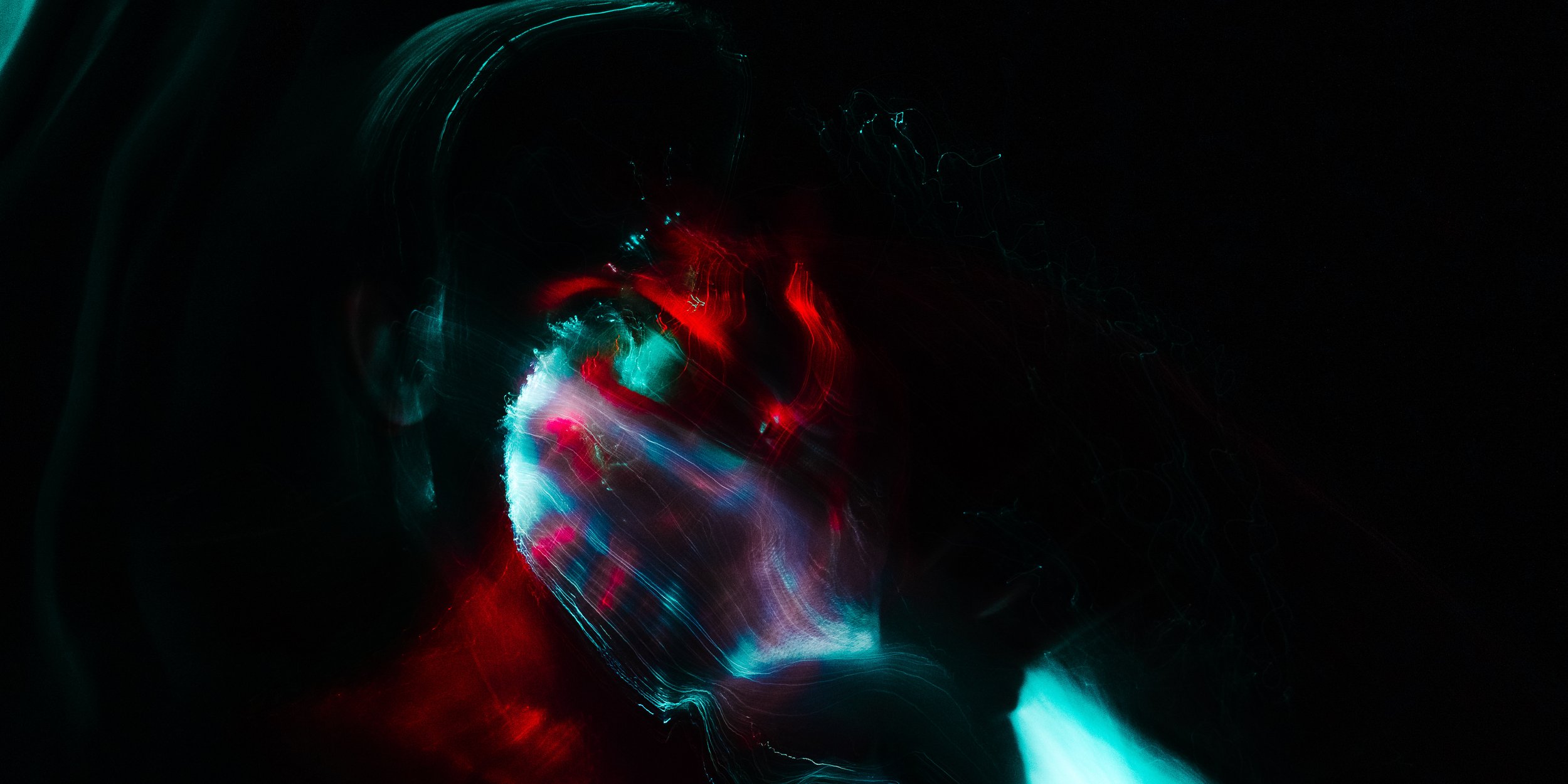 Abstract colorful light trails with red, blue, and white hues against a dark background, resembling a dynamic digital or cosmic scene.