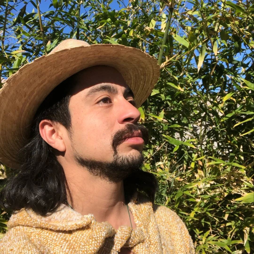 argonaut/permaculture designer in a landscapers hat with fruit tree in background