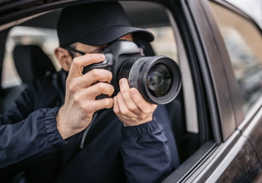 Modern wooden cabin in mountainous landscape with large window reflecting interior light.
