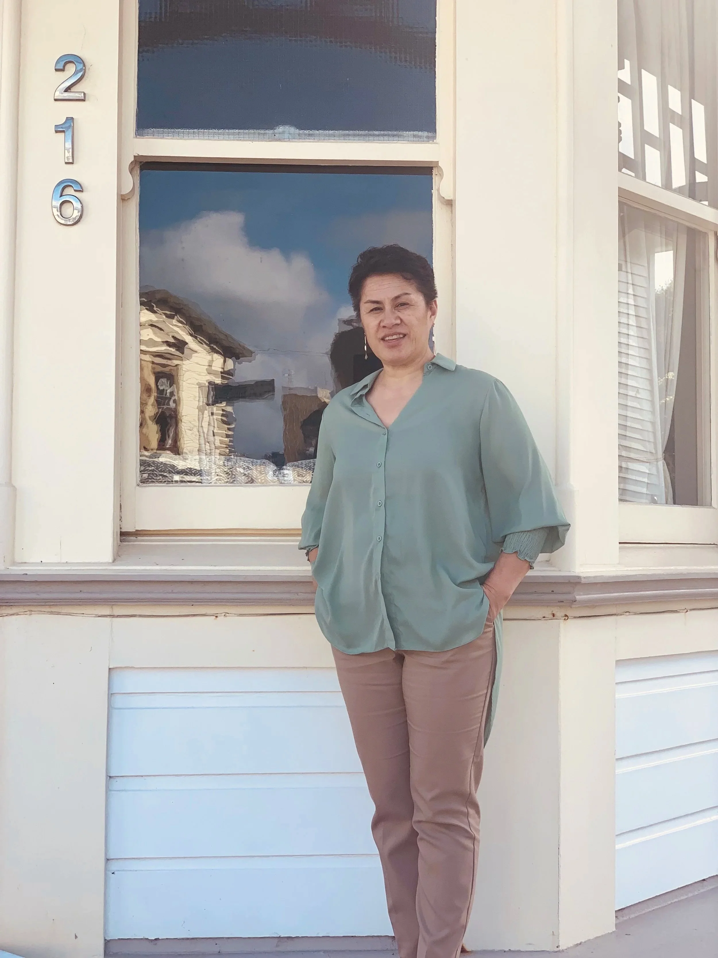A photo of Naomi standing in front of Kia Maia hostel