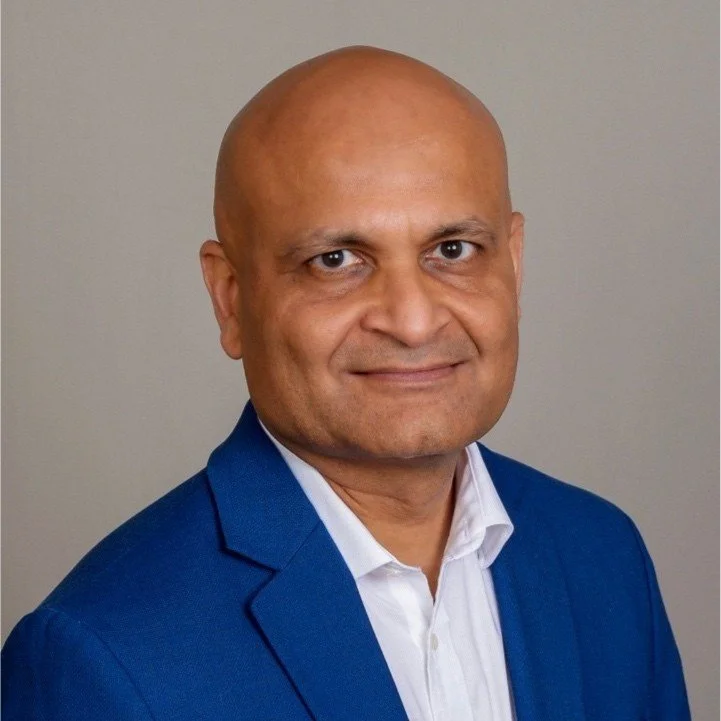 Bald man in a blue suit jacket and white shirt smiling.