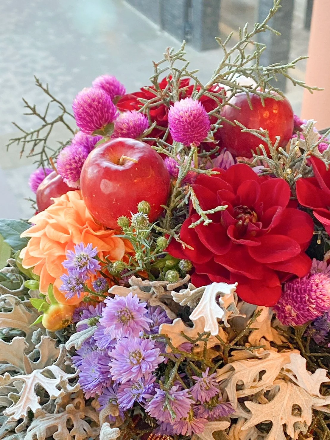 An autumn-coloured bouquet with apples and red dahlias
