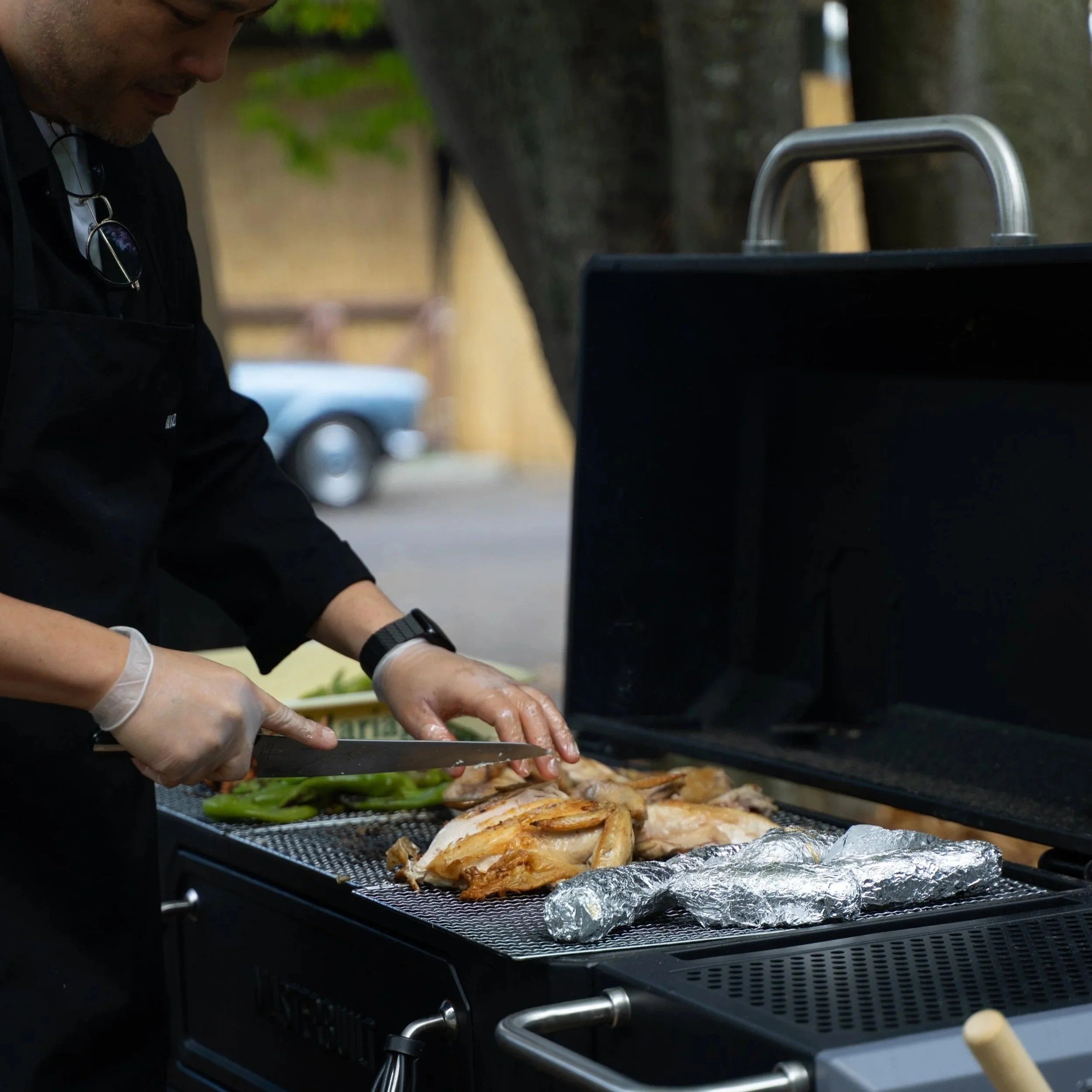 グリルの上で丸鳥を焼き上げるシェフの手元