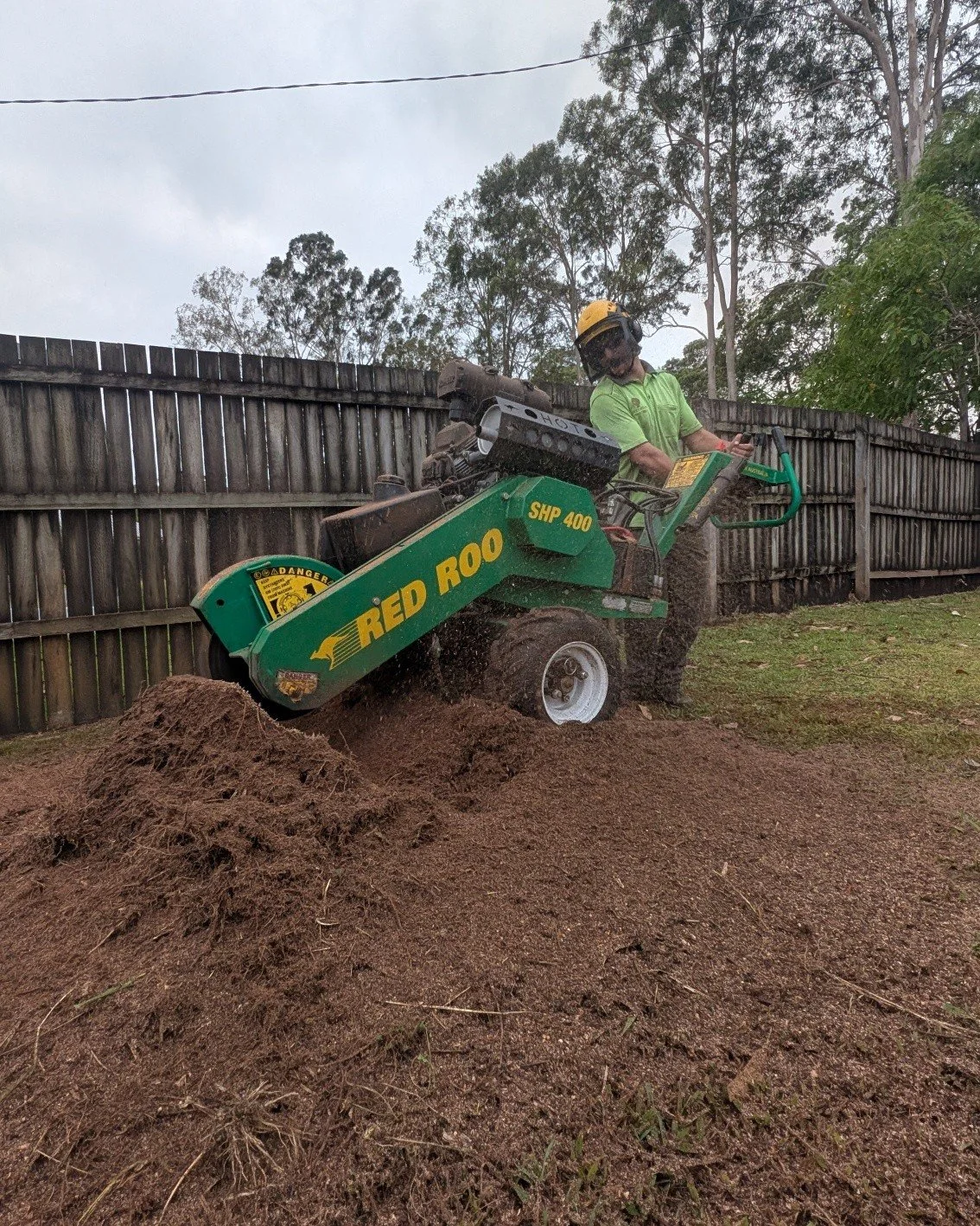 man using small stmup grinder with mulch all over ground in a backyard