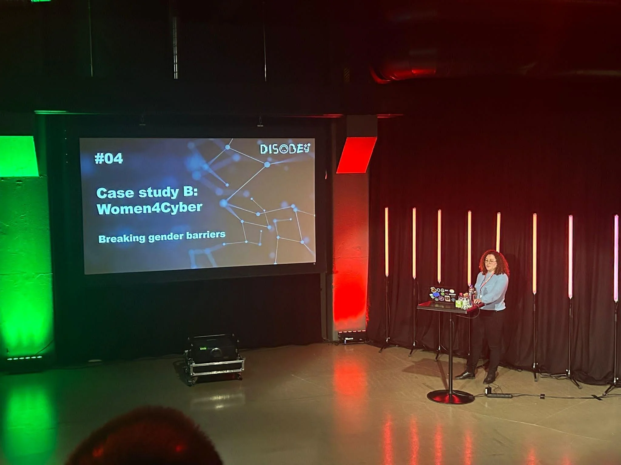 Photo of Bianca lecturing on stage about Women4Cyber