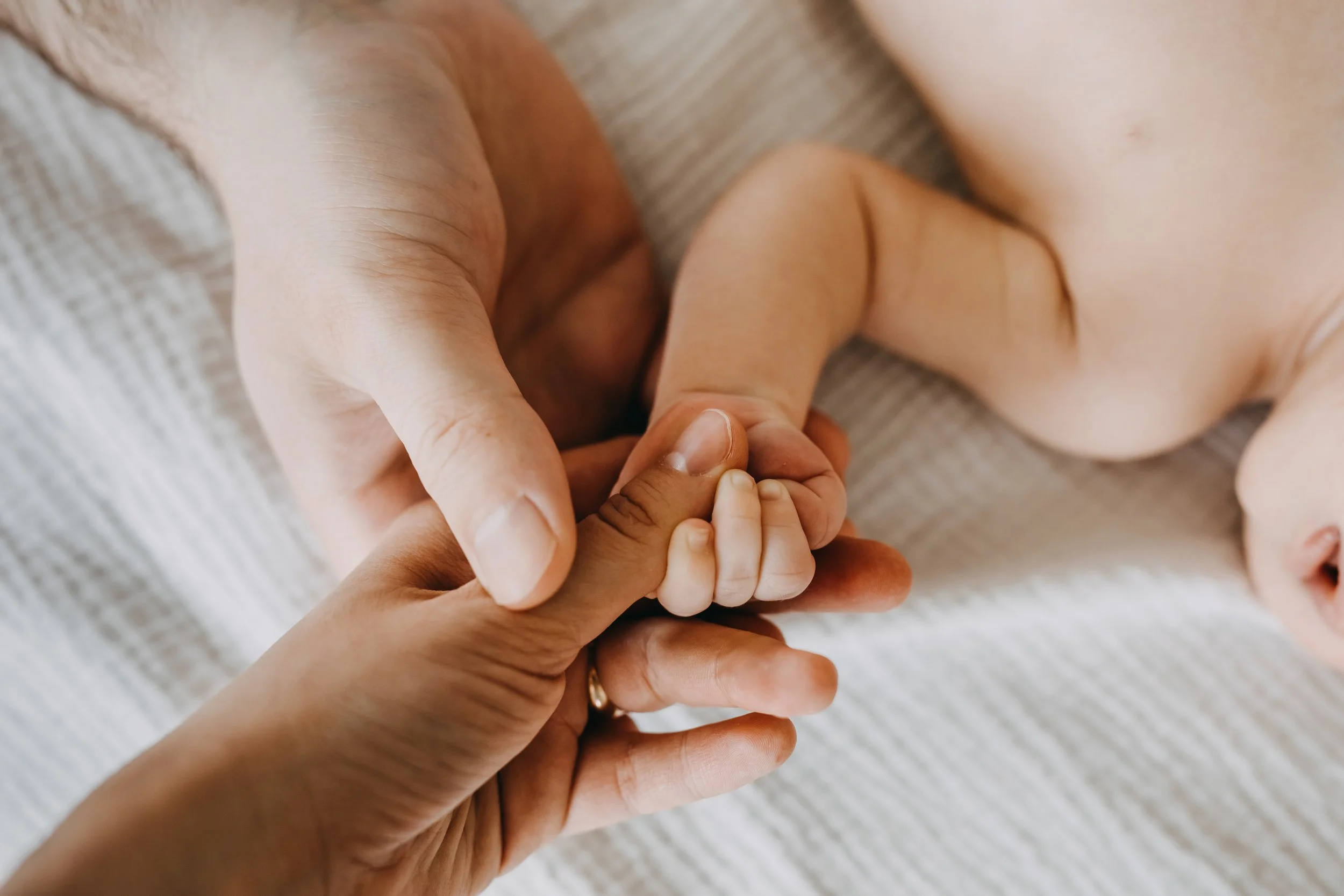 Parents holding the hand of their newborn baby