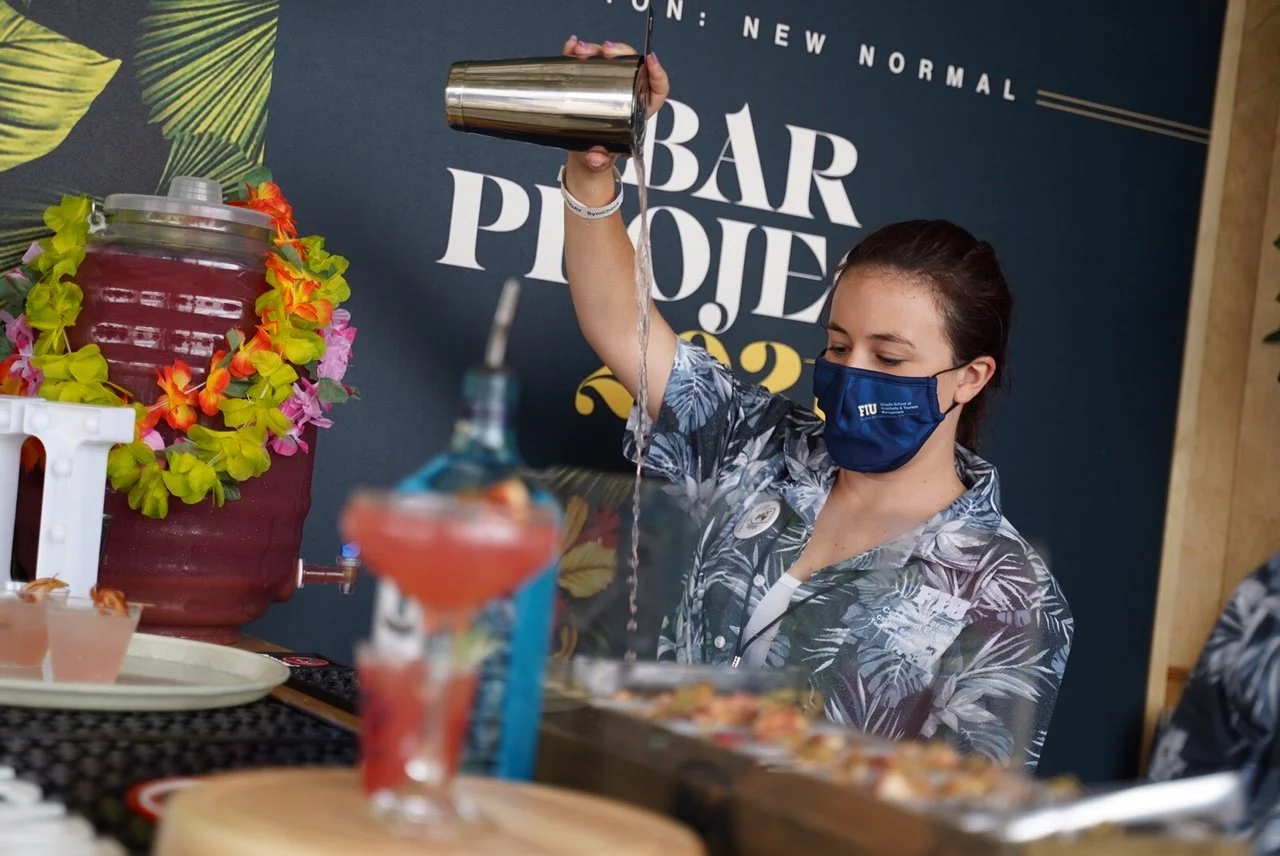 Two women pouring drinks at bar project.