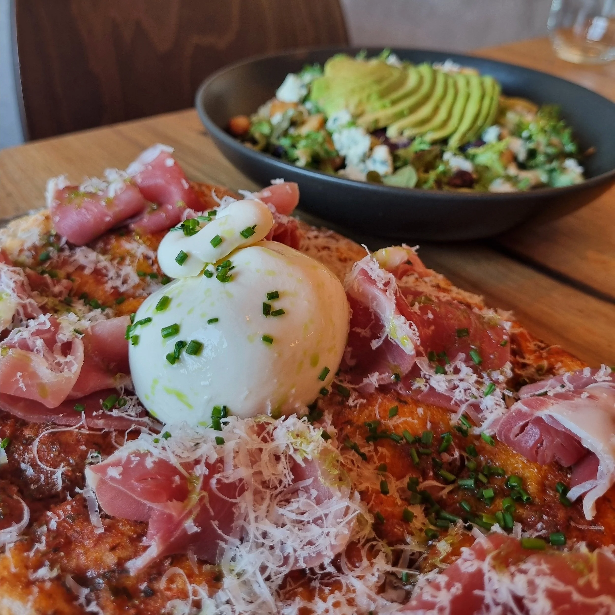 Pinsa Pizza, with Burrata and prosciutto, with our roasted red grape salad in the background