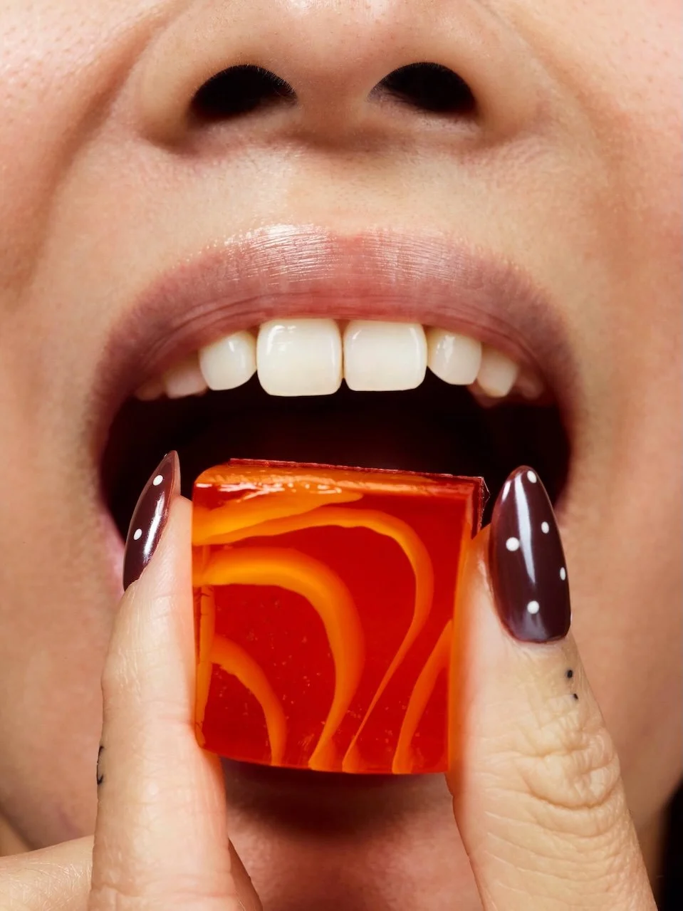 Close-up of someone biting into a Solid Wiggles jelly shot.