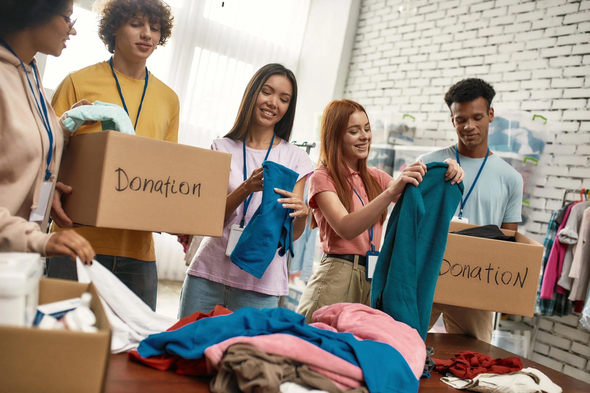 Family volunteering at a donation center, unpacking clothes from a box, with smiling parents and children.