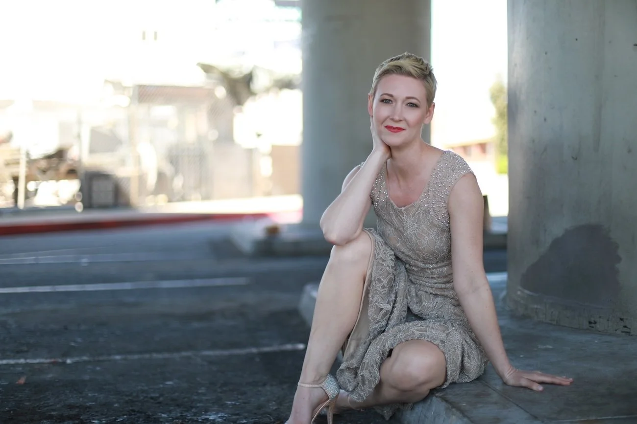Ashlee Lynn Espinosa sitting confidently in a neutral-toned dress beneath an architectural structure, symbolizing career clarity and strength.