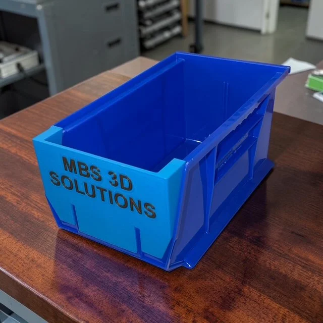 A blue Dillon ammo bin with an SL900 bin insert resting on a brown surface.
