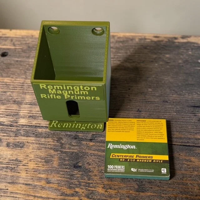 Remington No. 9 1/2 Magnum Rifle primer pack organizer sitting on wooden surface next to one primer pack.
