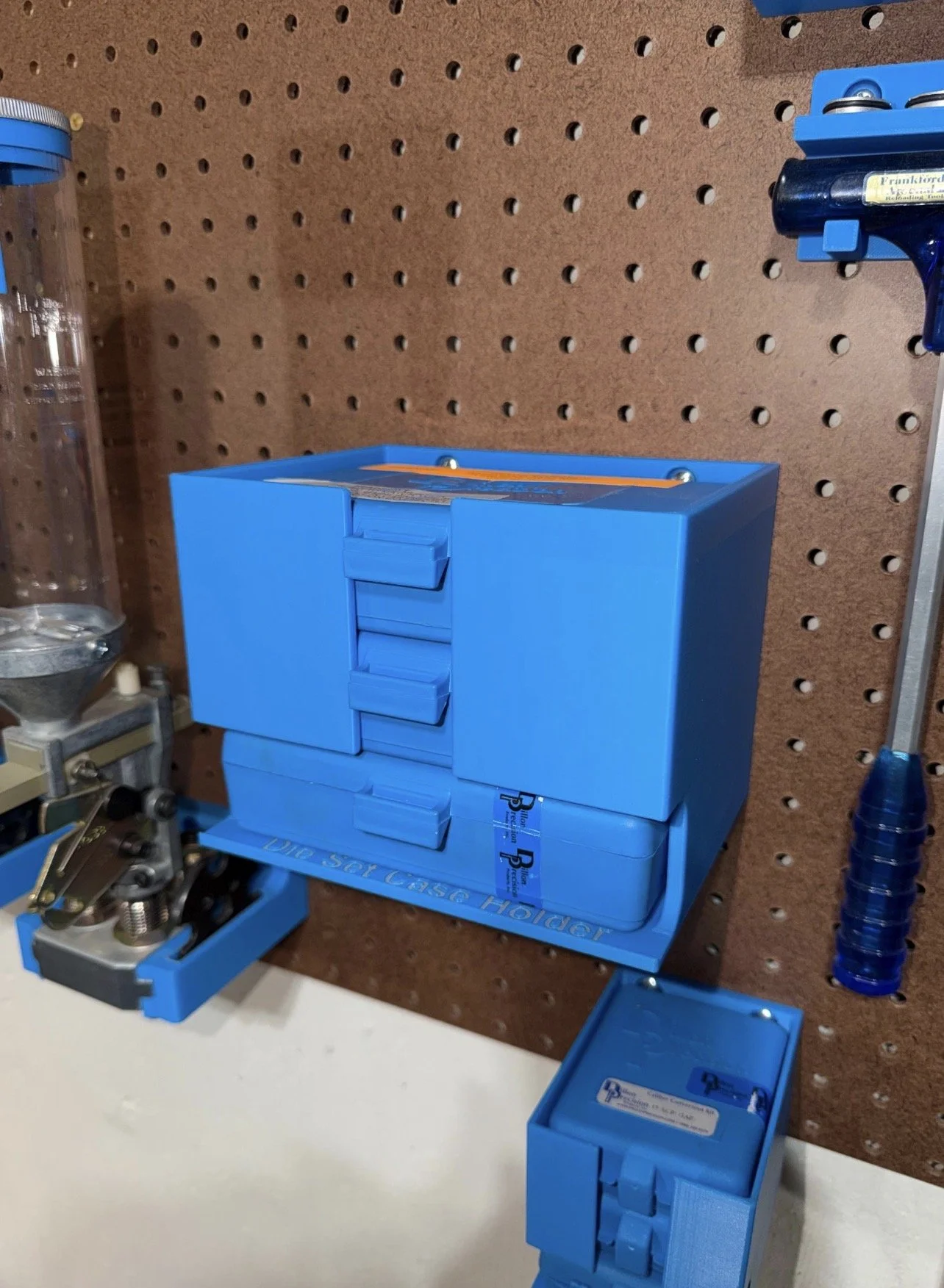 Dillon 550/650/750 die set case holder mounted on pegboard.