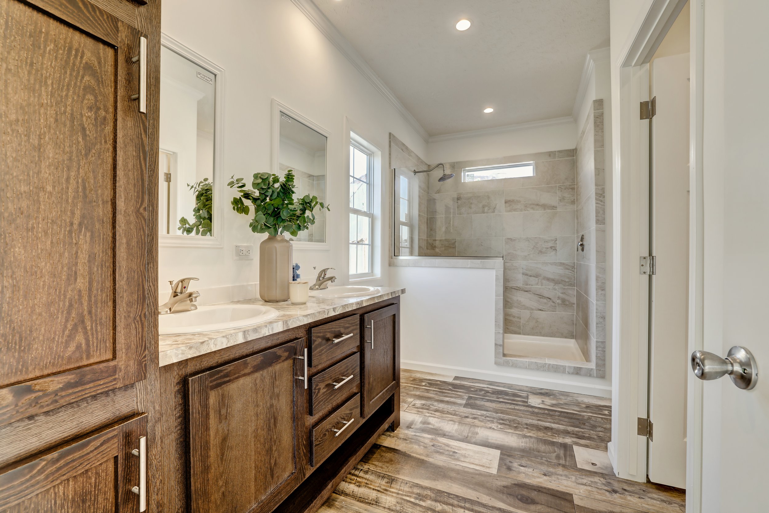 Modern bathroom with double sink vanity, large mirror, and glass-enclosed shower