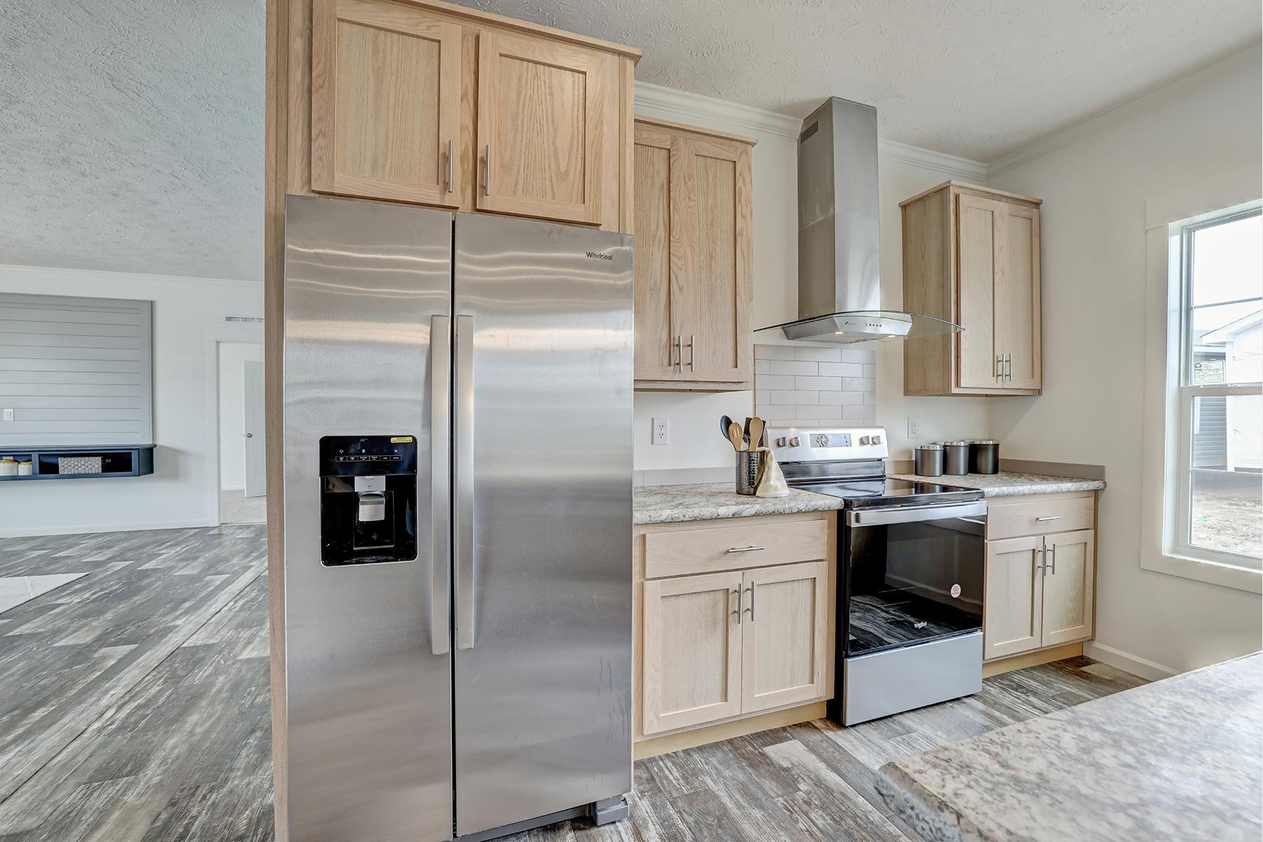 Modern kitchen with stainless steel refrigerator, wooden cabinets, electric range, and extractor hood.