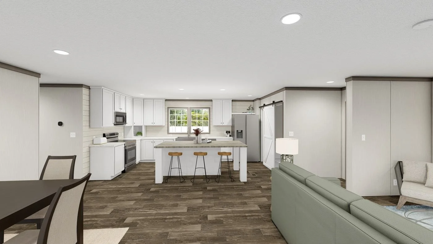 Open-concept living space with a modern kitchen featuring white cabinets, stainless steel appliances, and a central island with stools; adjacent living area with green sectional sofa and a dining table with chairs; wood flooring throughout.