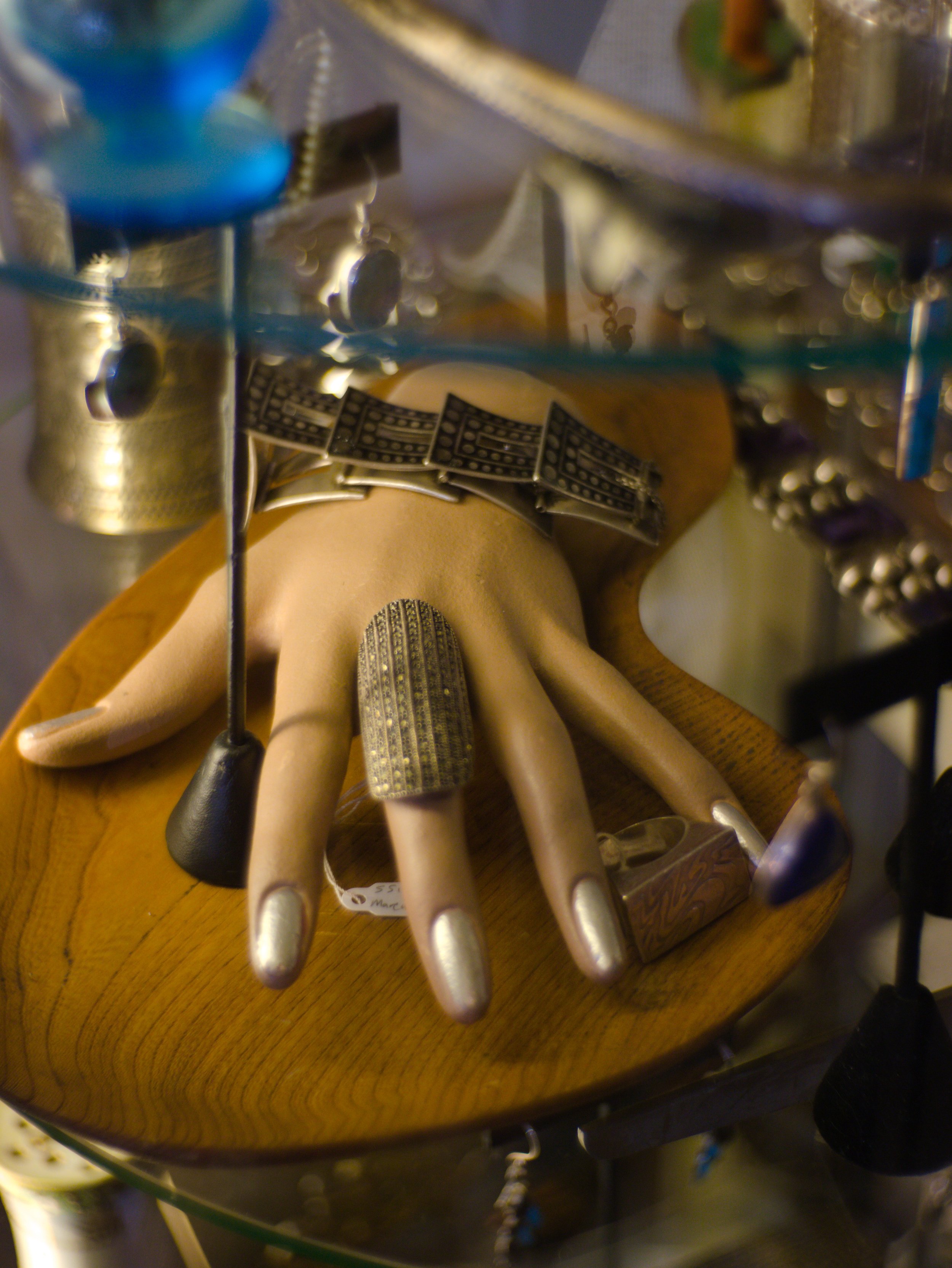 Close-up of a jewelry display featuring bracelets and rings, with a reflection in a glass surface.