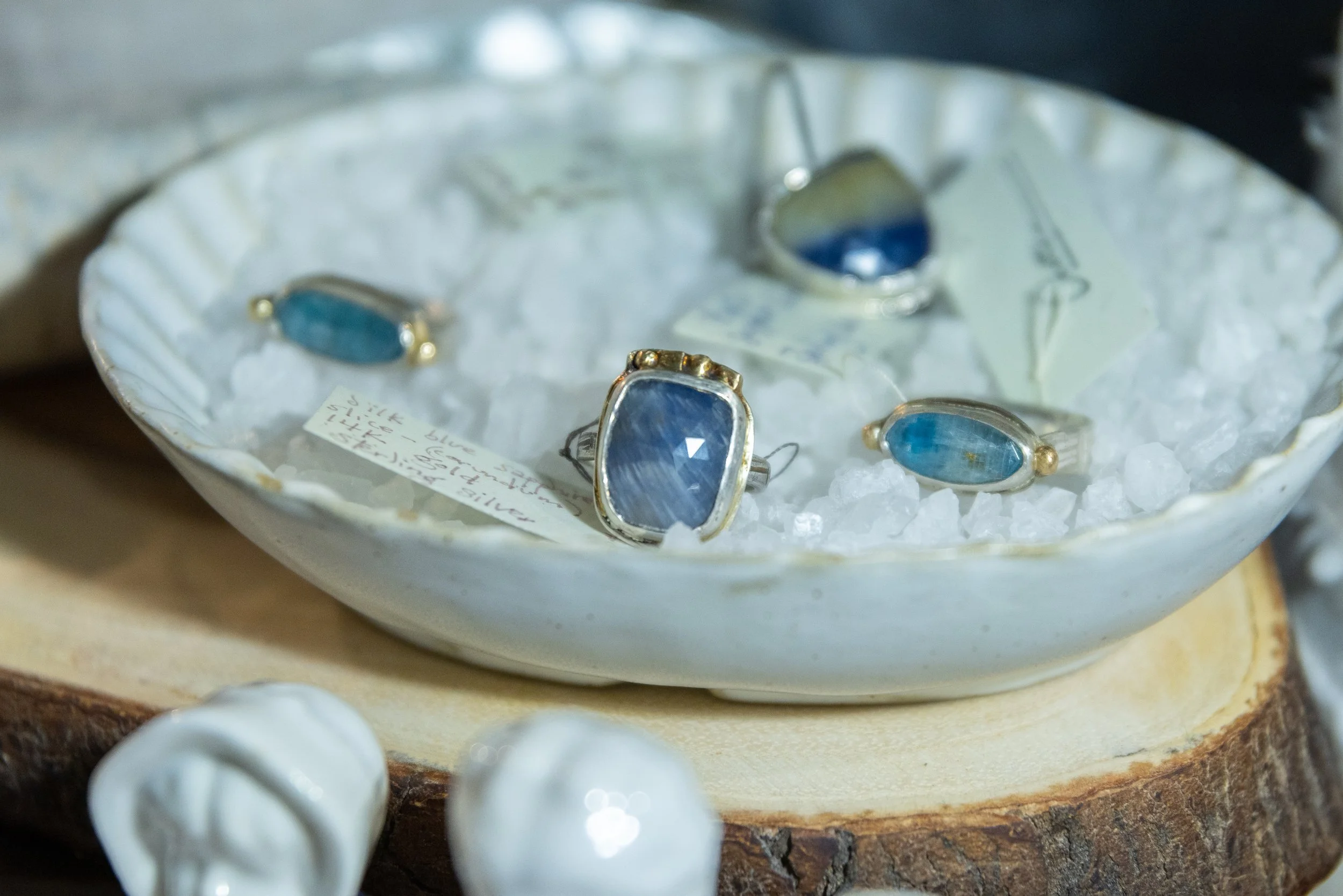 Jewelry display case with rings and a ring holder inside, set on a white surface with a dark background.