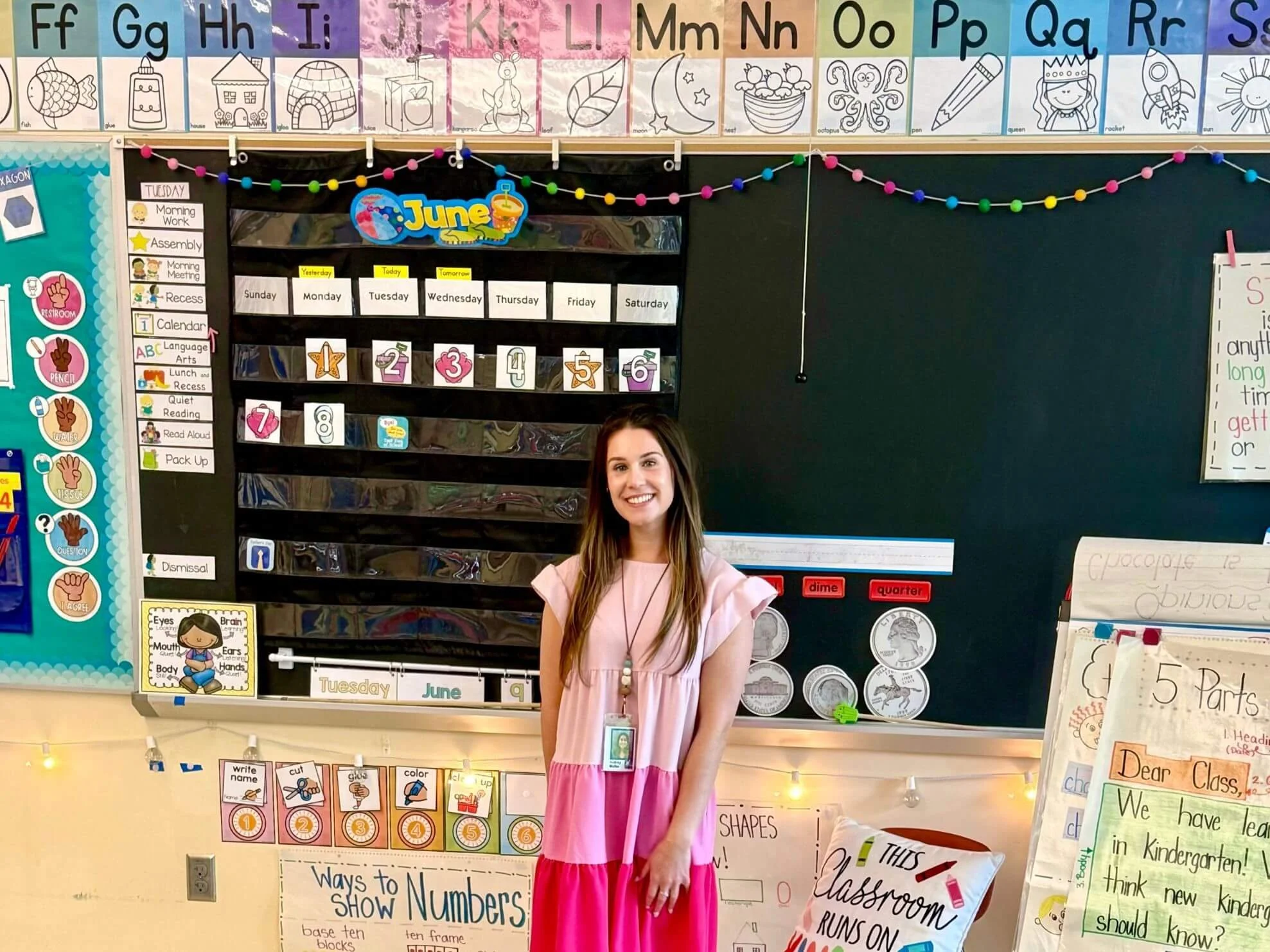 Audrey standing in front of chalkboard in a classroom with colorful school decorations.