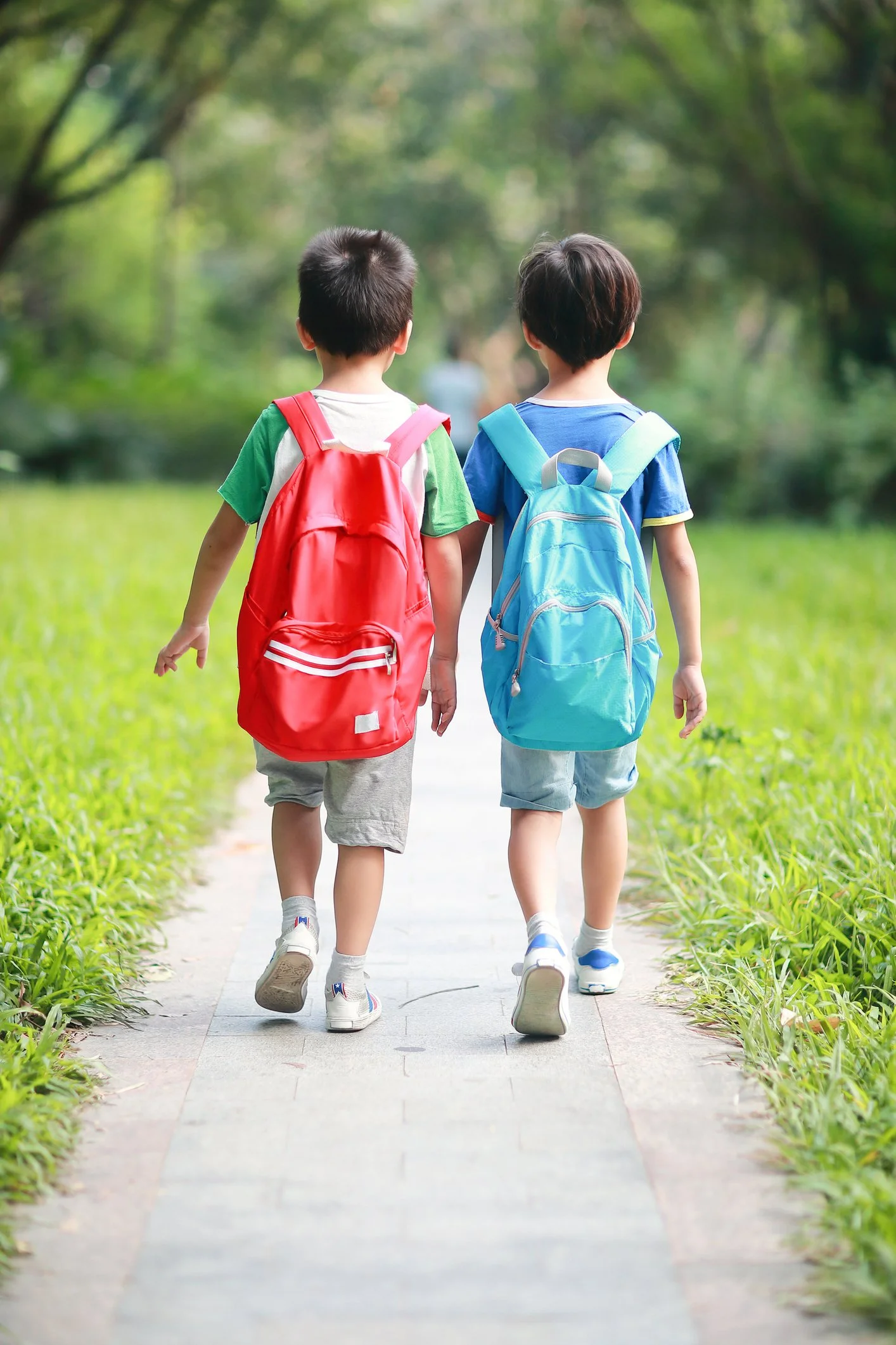 Two elementary students with backpacks walking to school.