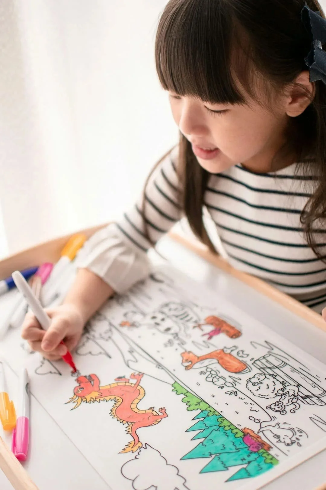 A young girl is coloring a picture at a table.