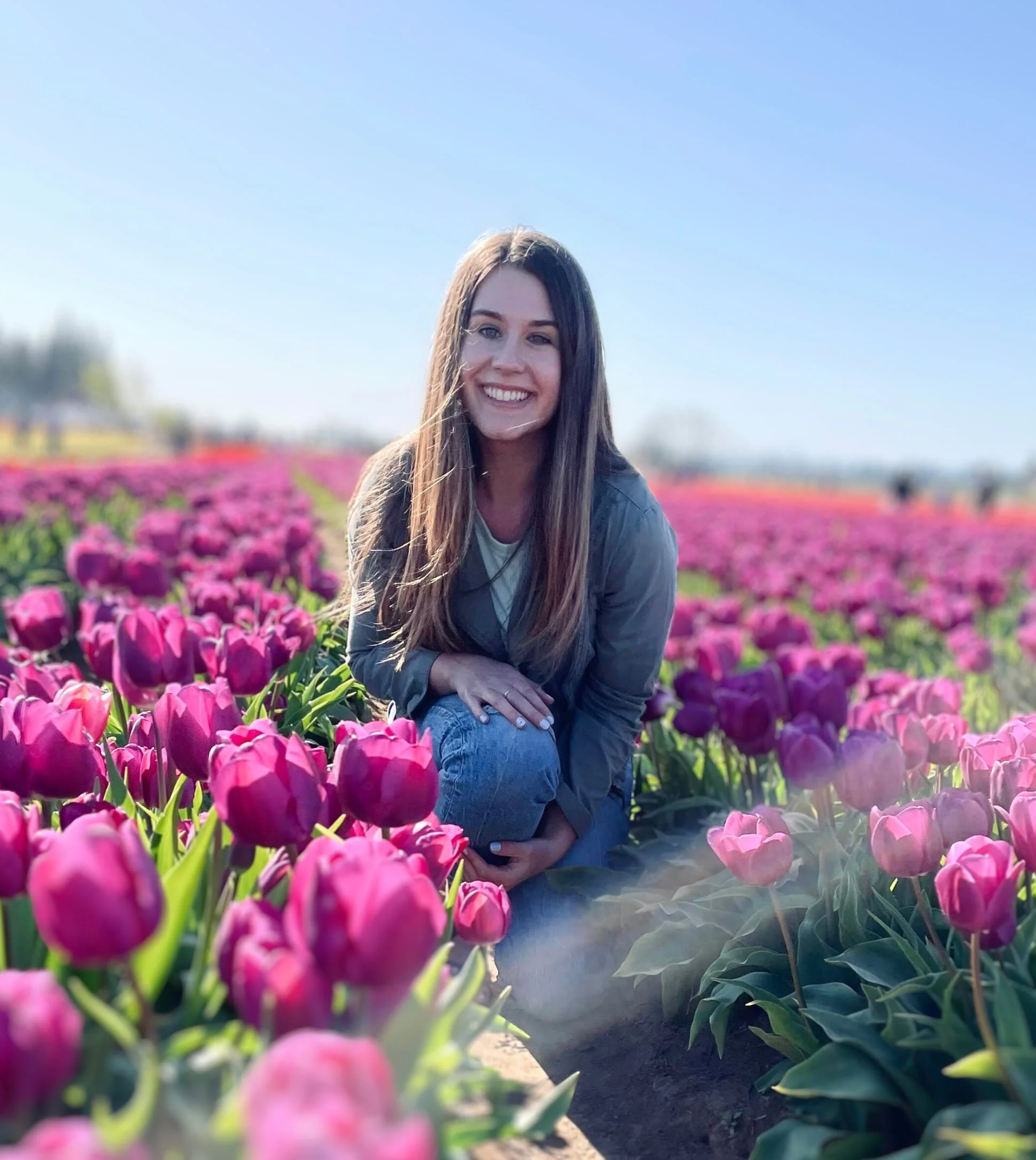Audrey Muller smiling while kneeling in a field of pink tulips.