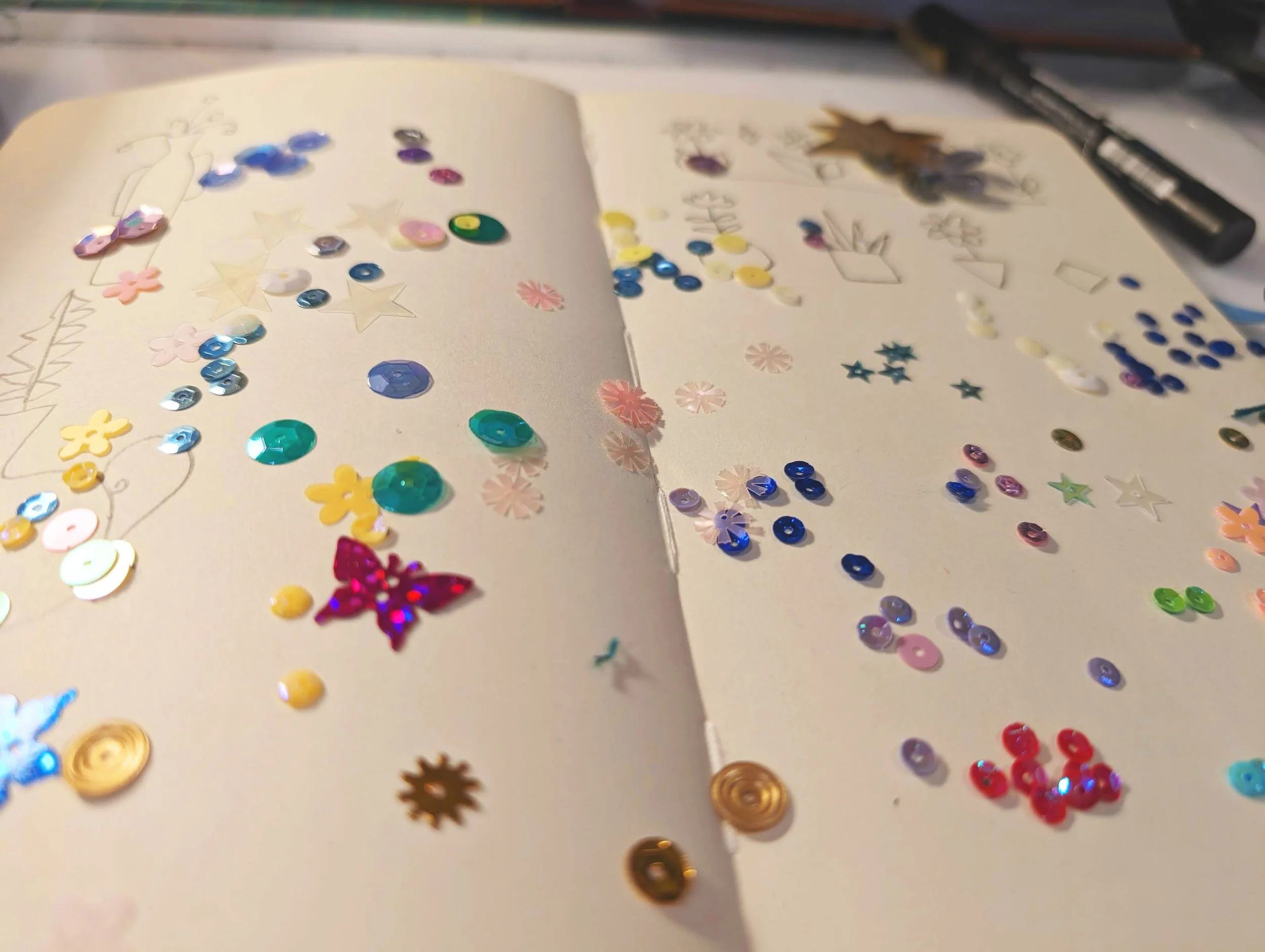 Closeup of sequins on an open sketchbook.