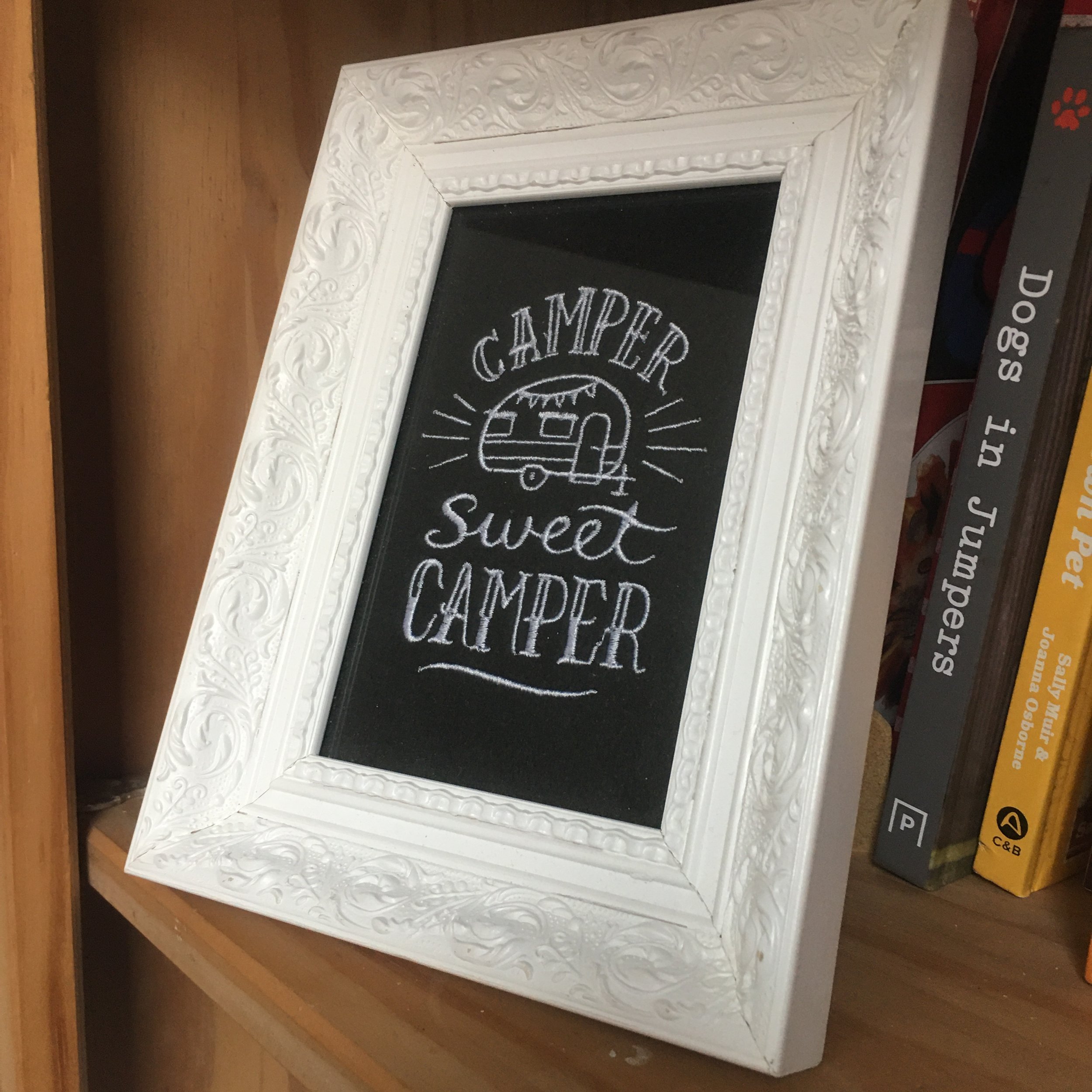 Decorative framed chalkboard sign reading "Camper Sweet Camper" with a drawing of a camper trailer.