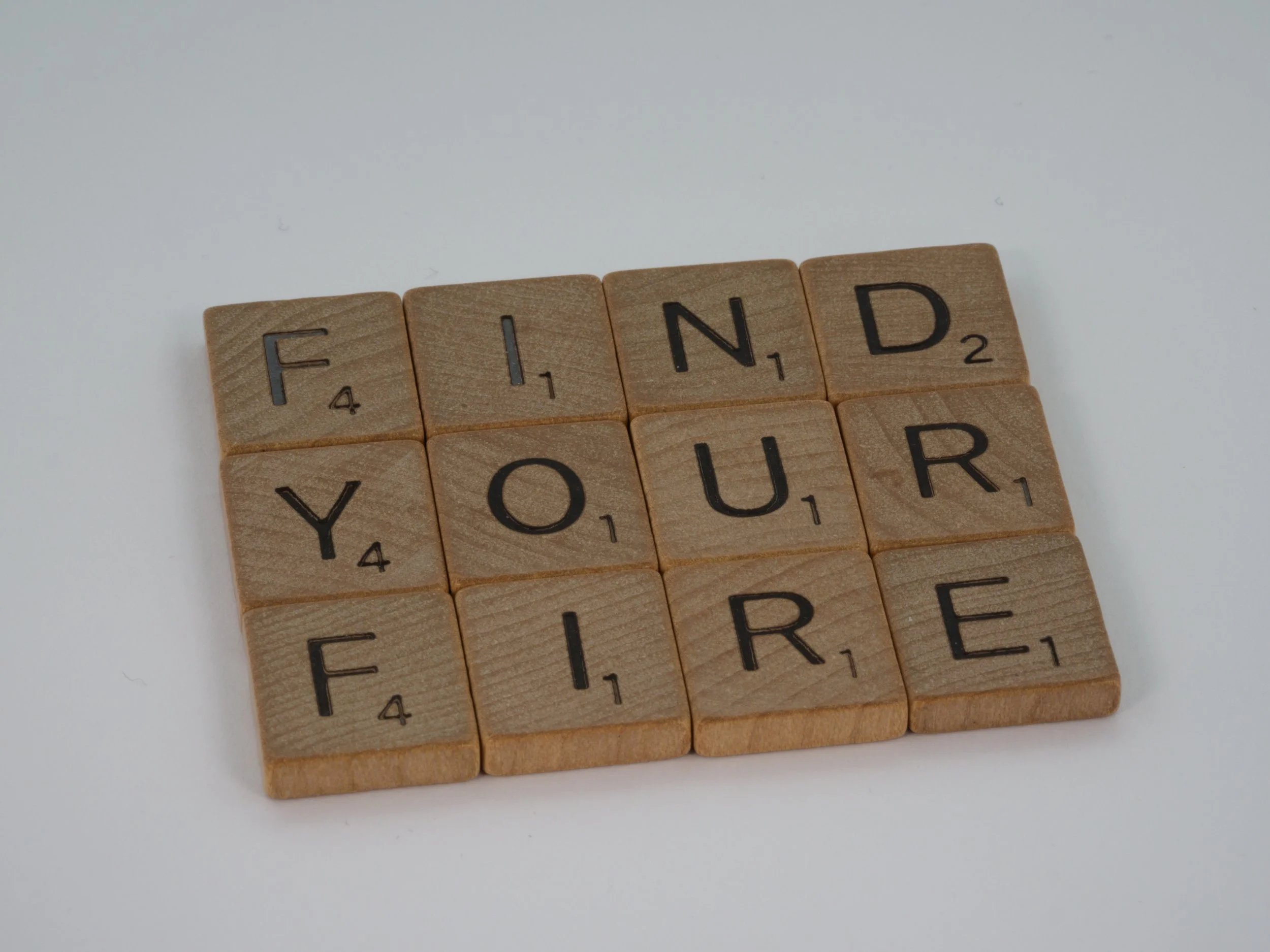 Scrabble tiles spelling out 'FIND YOUR FREEDOM' on a white surface.