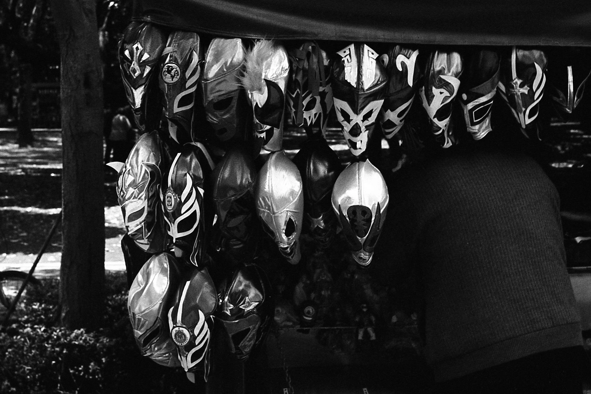 Black and white photo of lucha libre masks hanging on a stall
